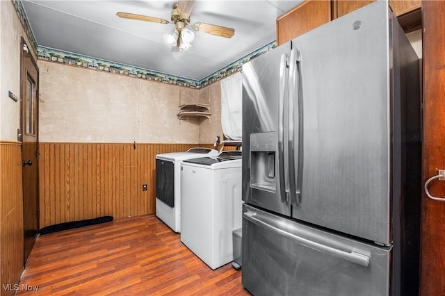 clothes washing area featuring ceiling fan, dark hardwood / wood-style flooring, independent washer and dryer, and wooden walls