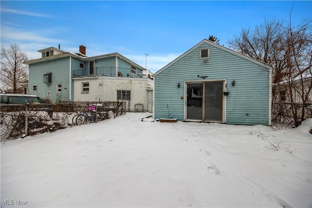 snow covered rear of property with a balcony