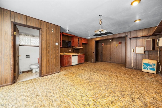 kitchen featuring carpet flooring, wood walls, and white dishwasher