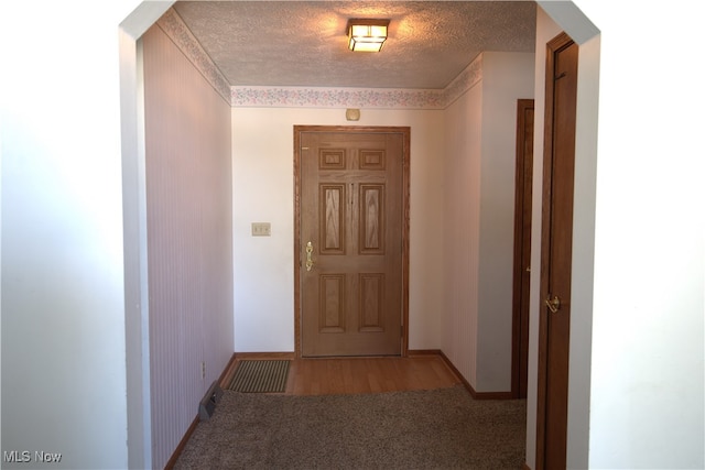 hallway featuring light colored carpet and a textured ceiling