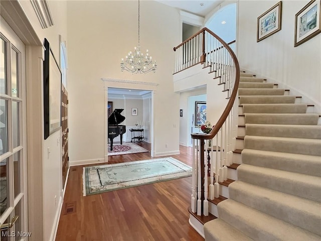 foyer featuring wood-type flooring, a high ceiling, and an inviting chandelier