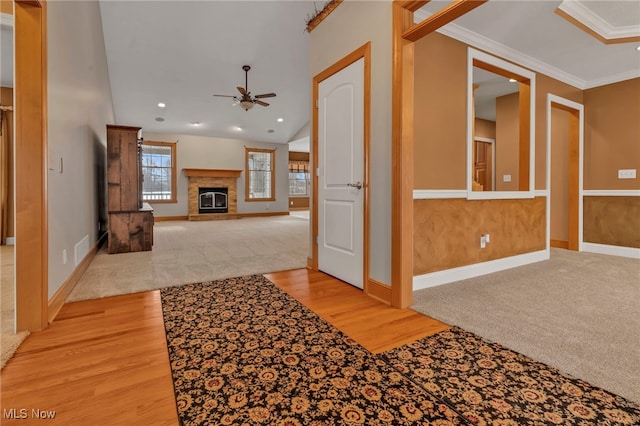 corridor featuring light hardwood / wood-style floors, crown molding, and vaulted ceiling