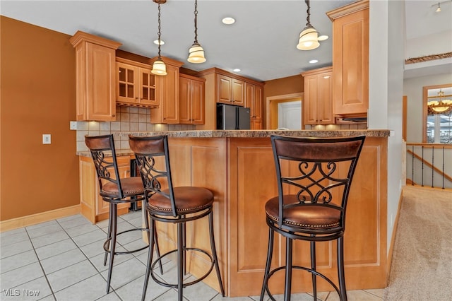 kitchen with kitchen peninsula, stainless steel fridge, a breakfast bar, and hanging light fixtures