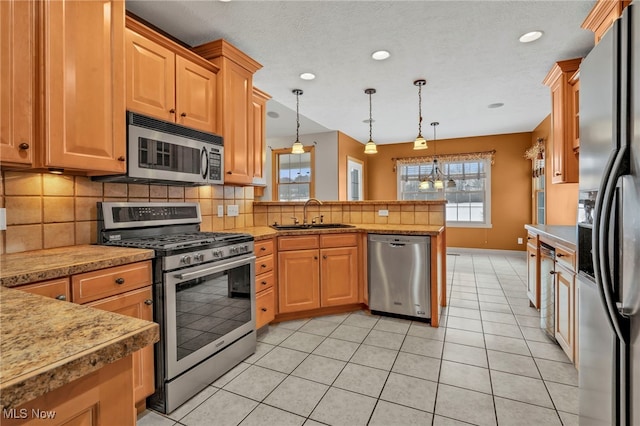 kitchen featuring hanging light fixtures, light tile patterned floors, sink, and appliances with stainless steel finishes