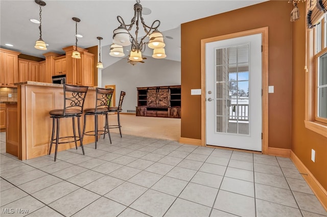 kitchen with a breakfast bar, pendant lighting, a chandelier, light brown cabinetry, and light tile patterned floors