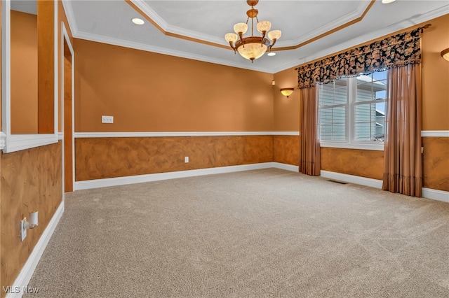 empty room with a chandelier, carpet floors, crown molding, and a tray ceiling