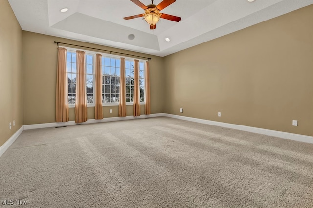 spare room featuring carpet, a raised ceiling, and ceiling fan