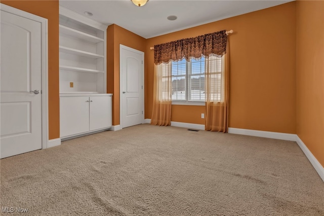 carpeted spare room featuring built in shelves