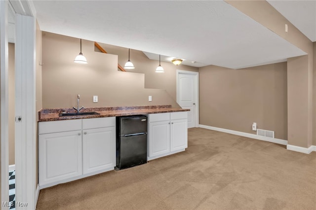 kitchen with white cabinetry, sink, refrigerator, decorative light fixtures, and light carpet