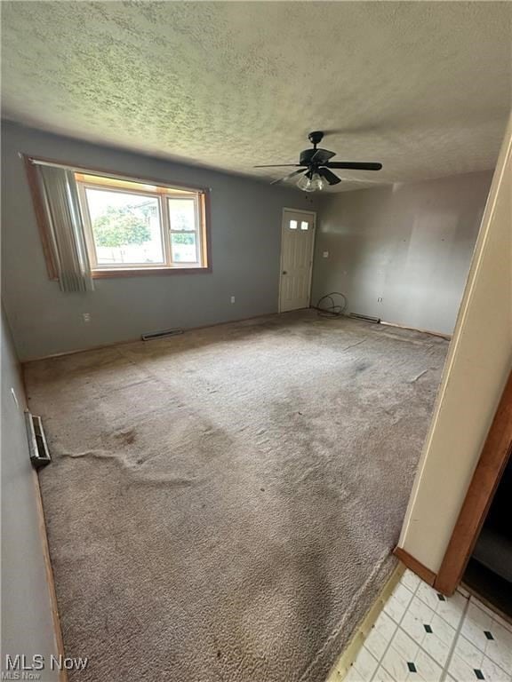 carpeted empty room featuring ceiling fan and a textured ceiling