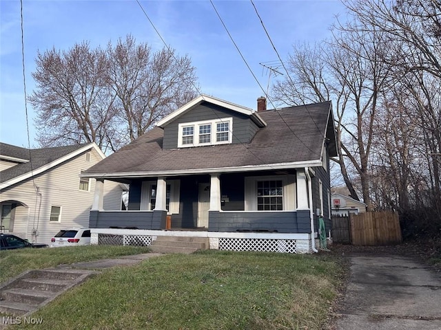 bungalow featuring covered porch and a front yard