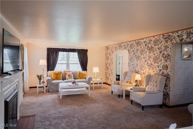 living area with carpet, arched walkways, a fireplace with flush hearth, baseboards, and wallpapered walls