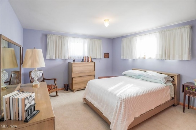 bedroom with multiple windows and light colored carpet