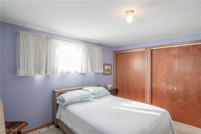 bedroom with carpet floors and two closets