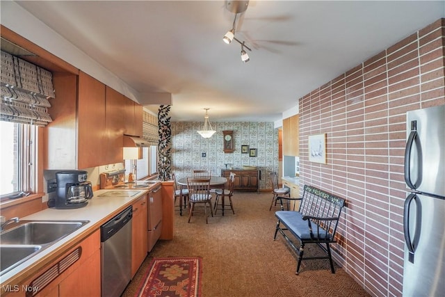 kitchen with pendant lighting, light colored carpet, sink, and appliances with stainless steel finishes