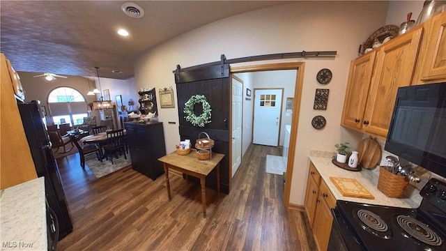 kitchen with a barn door, dark hardwood / wood-style flooring, pendant lighting, black appliances, and ceiling fan with notable chandelier