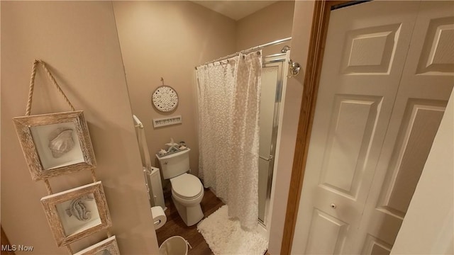 bathroom featuring curtained shower, wood-type flooring, and toilet