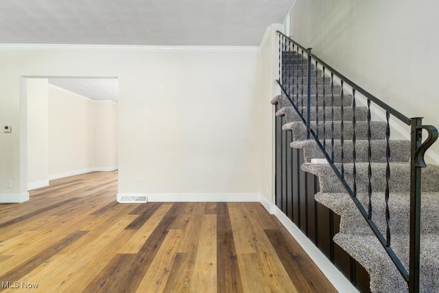 stairs featuring hardwood / wood-style flooring and crown molding