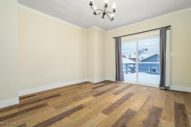 spare room featuring hardwood / wood-style floors, ornamental molding, and a chandelier