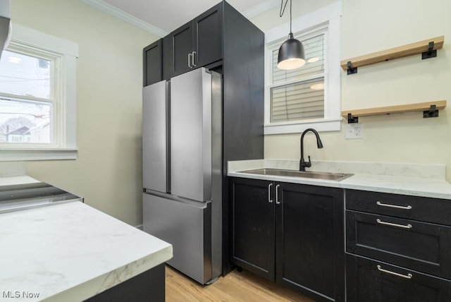 kitchen featuring stainless steel fridge, light wood-type flooring, crown molding, sink, and pendant lighting