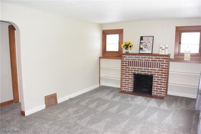 unfurnished living room featuring carpet flooring, a fireplace, and a healthy amount of sunlight