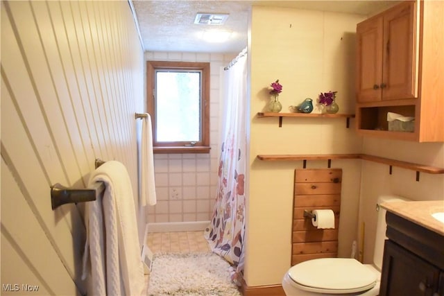 bathroom featuring wood walls, a textured ceiling, toilet, vanity, and a shower with shower curtain