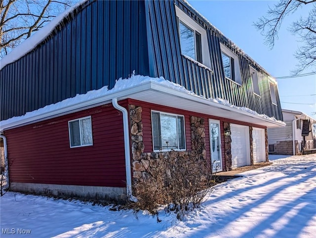 snow covered property with a garage