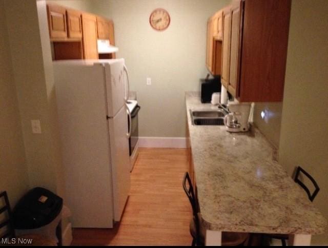 kitchen with sink, white fridge, light hardwood / wood-style floors, exhaust hood, and range