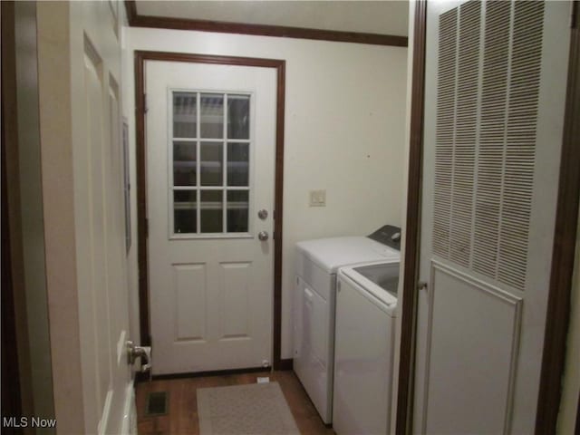 clothes washing area with ornamental molding, laundry area, separate washer and dryer, and dark wood-style flooring