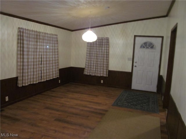 interior space featuring wallpapered walls, ornamental molding, dark wood finished floors, and a wainscoted wall