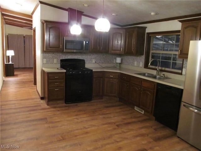 kitchen with pendant lighting, light countertops, a sink, wood finished floors, and black appliances