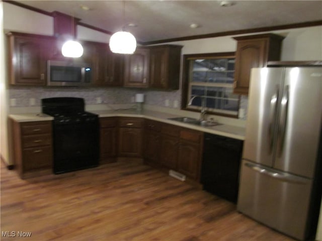 kitchen with dark wood-type flooring, a sink, light countertops, dark brown cabinets, and black appliances