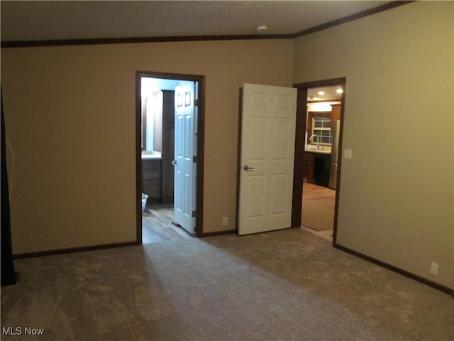 spare room featuring a sink, baseboards, crown molding, and carpet flooring