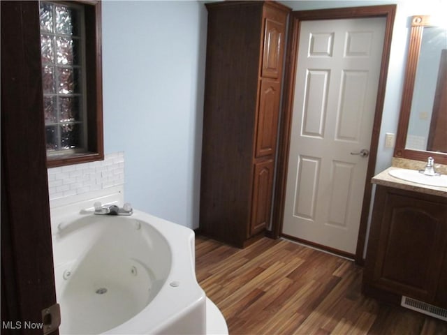 bathroom with a whirlpool tub, wood finished floors, vanity, and visible vents