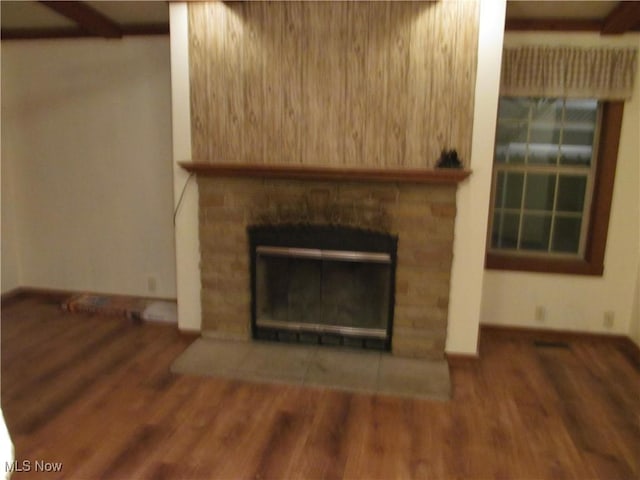 unfurnished living room featuring baseboards, wood finished floors, and a glass covered fireplace