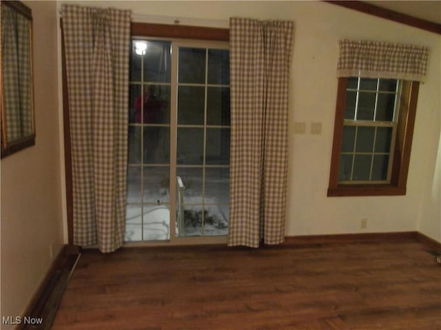 spare room featuring dark wood-type flooring and baseboards