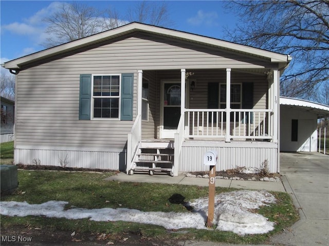 manufactured / mobile home featuring a porch, an attached carport, and concrete driveway