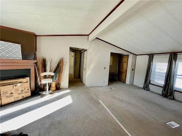 unfurnished living room featuring carpet, vaulted ceiling with beams, a fireplace, and a textured ceiling