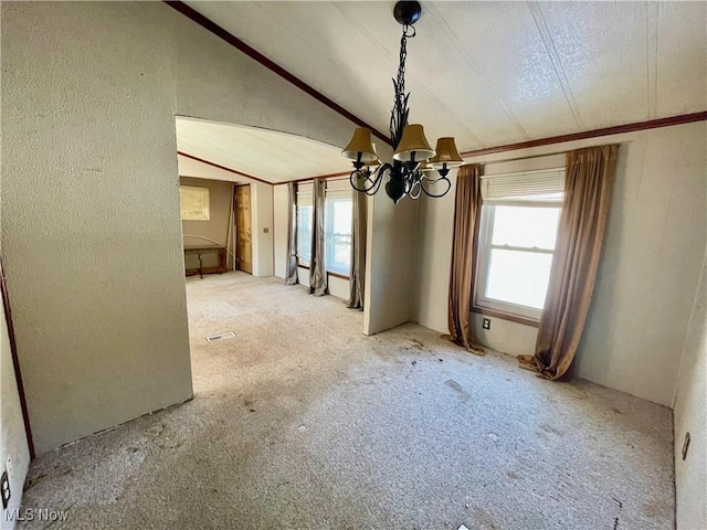 unfurnished dining area with carpet, lofted ceiling, an inviting chandelier, and a healthy amount of sunlight