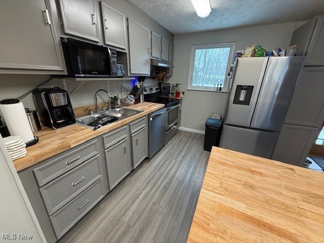 kitchen featuring wooden counters, gray cabinetry, a textured ceiling, stainless steel appliances, and sink