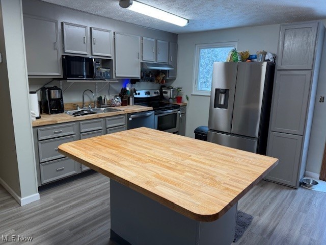 kitchen with a textured ceiling, stainless steel appliances, sink, hardwood / wood-style flooring, and gray cabinets