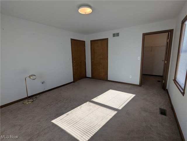 unfurnished bedroom with light colored carpet, a closet, and a walk in closet