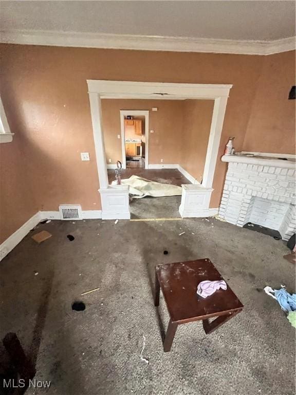 unfurnished living room with ornamental molding and a fireplace