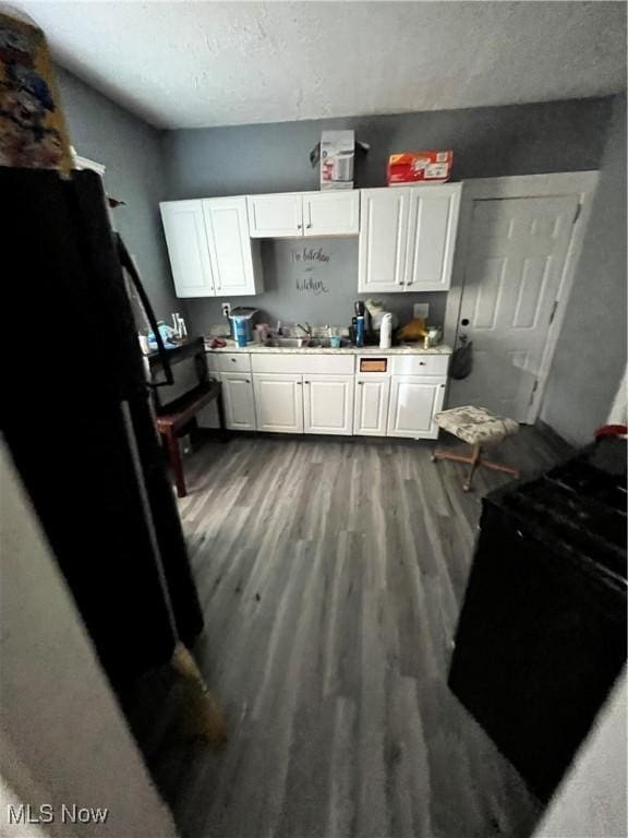 kitchen featuring white cabinets, sink, electric range, a textured ceiling, and wood-type flooring