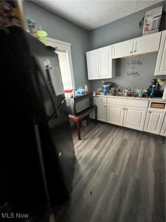 kitchen with black appliances, white cabinetry, and a textured ceiling