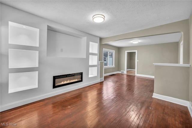 unfurnished living room with dark wood-type flooring and a textured ceiling