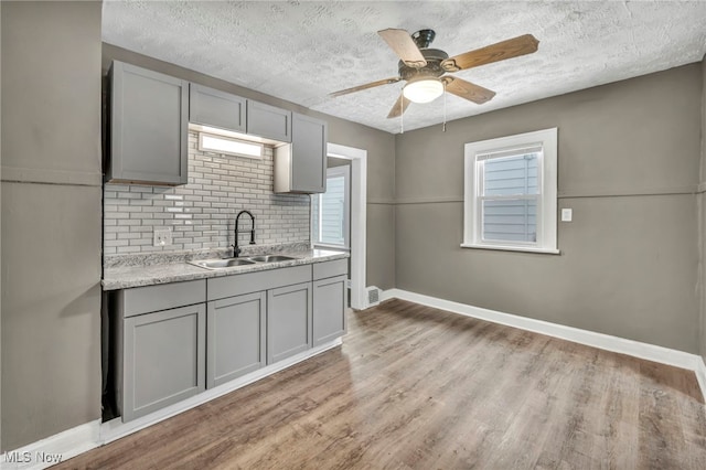 kitchen with gray cabinetry, a wealth of natural light, sink, and light hardwood / wood-style floors