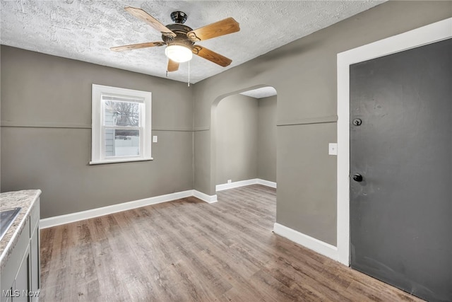 unfurnished dining area featuring ceiling fan, light hardwood / wood-style floors, and a textured ceiling