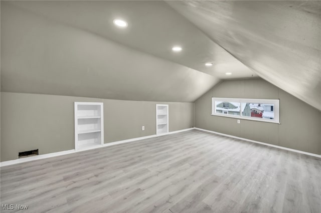 additional living space featuring built in shelves, light hardwood / wood-style floors, and lofted ceiling