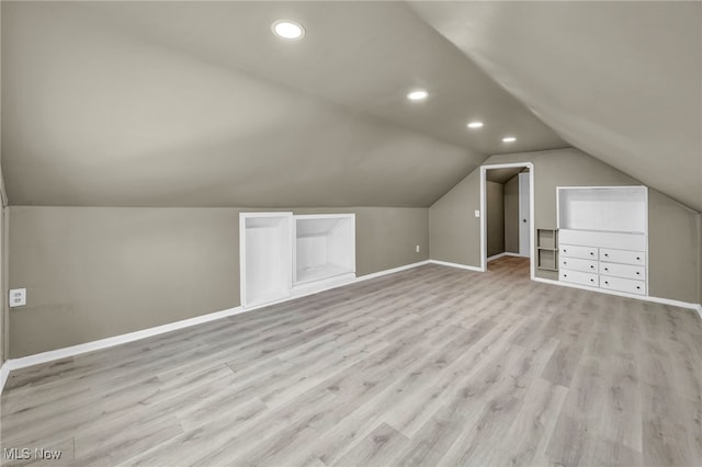 bonus room featuring built in shelves, light hardwood / wood-style flooring, and lofted ceiling